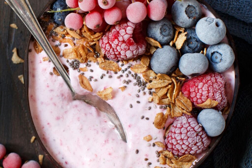 Close-up of a vibrant pink smoothie bowl adorned with fresh blueberries, raspberries, and chia seeds