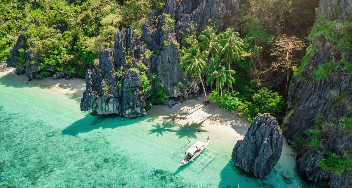 A bangka boat moored at a white sandy beach in the Philippines